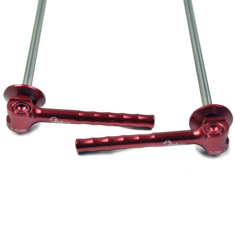 Close-up of red OMNI Racer World quick-release wheel skewers, 2-pack, aluminum, 41 g total, outdoors