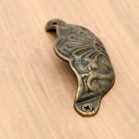 Prime Sleek Distressed Antique Brass Seashell Cabinet Pulls 8 Piece Set Embossed Furniture Cup Handles close-up detail on wooden surface.