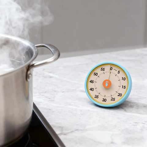 Dual Mode 60 Minute Mechanical Kitchen Timer With Magnetic Back And Built In Stand For Cooking And Baking on a marble countertop.