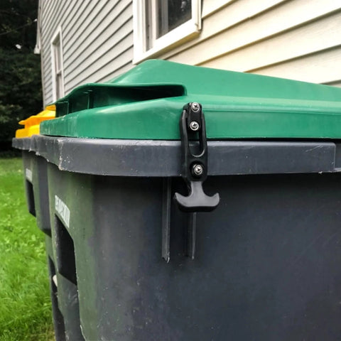 Rubber T-handle draw latch, black, side view securing green trash can lid.