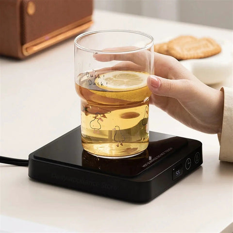 Never Suffer Through Lukewarm Coffee Again With This 20W Adjustable Mug Warmer keeping a glass of lemon drink hot on desk.