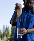 Using the Peak Series Collapsible Water Filter Bottle 1L Squeeze Hydration System outdoors to filter into a glass.