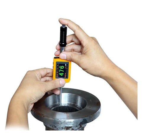 Hands using Dead Accurate Digital Leeb Pen Type Hardness Meter on metallic part, measuring hardness with OLED display.