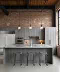 Contemporary kitchen with gray wood cabinets, stainless steel appliances, and industrial lighting, showcasing a sleek modern design.