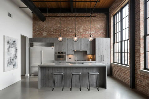 Contemporary kitchen with gray wood cabinets, stainless steel appliances, and industrial lighting, showcasing a sleek modern design.