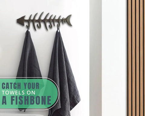 Heavy Duty Cast Iron Wall Hook Rack Featuring A Badass Fish Bone Skeleton Layout With Four Chunky Rustic Hooks and towels hanging.
