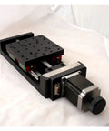 Top Shelf Precision Motorized Rotary Positioning Stage Featuring Slick Electric Linear Slide And Smooth Riding Worm Gear Drive For Heavy Duty Optics Setup Includes NT102TA500M Cross Module Rail System, viewed from the side showing the rail system and linear drive.