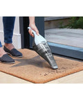 Using Cordless Handheld Vacuum Cleaner For Home And Car With Crevice Attachment on a doormat to clean dirt, showing bagless design.