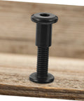 Top Shelf Five Piece Pack Of Black Stainless Steel Binding Screws And Nuts For Scrapbooks Photo Albums And Bookbinding With Countersunk Flat Head For No Sweat Setup, single screw on wooden surface.