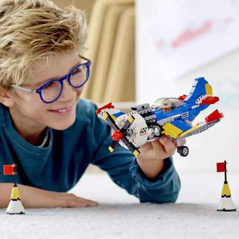 Child playing with Creator 3in1 Race Plane Build Kit With Helicopter And Jet Modes, 333-Piece Set, featuring open cockpit and rotating propeller.