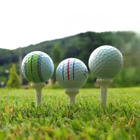Three golf balls on Big Easy White Golf Tees Set With 0.75 Inch Big Head 3.25 Inch Adjustable Height on grassy course
