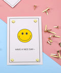 500 Piece Mini Brass Paper Fasteners Gold Pin Backs on card with smiley face, used for stationery and craft projects.