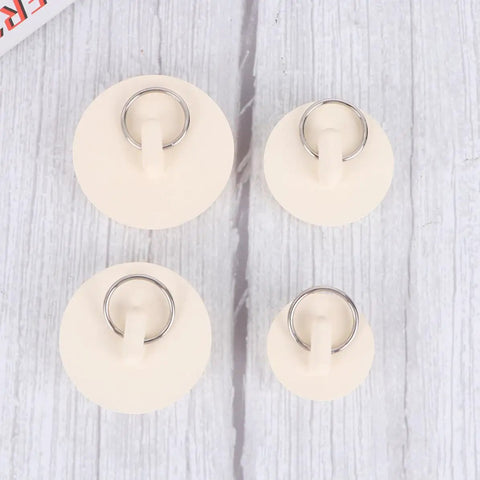 4pcs White Rubber Bathtub Stopper with Hanging Ring for Sink Drains displayed on a wooden surface, showing different sizes and details.
