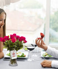 Couple at romantic dinner with bouquet and ring box on table