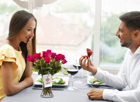 Couple at romantic dinner with bouquet and ring box on table
