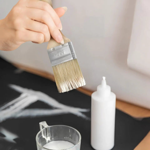 Hand holding Pro Grade Oil Based Paint Brush from 30 Pack with Thick 12mm Wood Handle and 2 Inch Stain Brush for smooth coverage