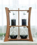 Heavy Duty Dutch Cold Brew Coffee Maker With Solid Wood Tower And Stainless Steel Filter brewing iced coffee with glass vessels.
