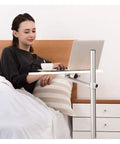 Adjustable Rolling Laptop Desk With Spacious Aluminum Top And Quick Height Adjustments used bedside, woman with laptop in bed.