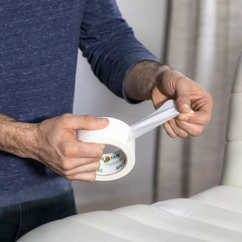 Person using Heavy Duty White Duct Tape 3 Pack 1.88 Inch By 30 Yard Rolls for repair on vinyl surface, showing strong adhesion.