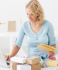 Person holding Beige Kraft Bubble Mailers With Self Seal Closure, organized desk setting.