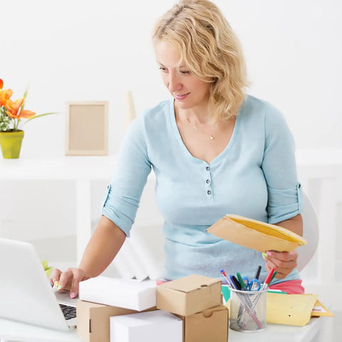 Person holding Beige Kraft Bubble Mailers With Self Seal Closure, organized desk setting.