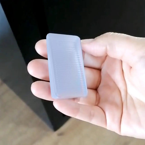 Hand holding a clear wedge shim from Clear 8 Pack Shims For Leveling Furniture Doors And Floors Trimmable Plastic Wedge Shims For Tables Toilets And Cabinets Rubber Texture Leveler Wedges With Adjustable Heights From 2mm To 10mm So You Can Fix Uneven Surfaces Easily.