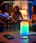Lit RGBIC Smart Table Lamp 2 With Touch Control, displaying colorful light on a table with people in the background.
