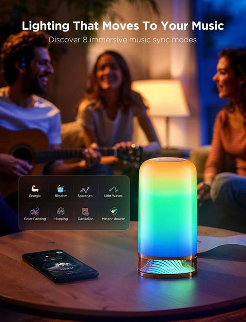 Lit RGBIC Smart Table Lamp 2 With Touch Control, displaying colorful light on a table with people in the background.