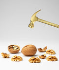Hand holding mini claw hammer over walnuts, illustrating tool use for Six In One Mini Hammer And Screwdriver Set Portable Multitool.