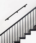 Kick Ass Heavy Duty Wall Mount Handrail in Matte Black Stainless Steel on wall beside indoor stairs for safe grip.