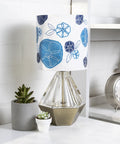 Table lamp with blue floral shade next to succulents and clock on white shelf