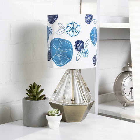 Table lamp with blue floral shade next to succulents and clock on white shelf