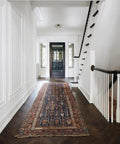 Intricate patterned area rug in a modern hallway with dark wood flooring and white paneling.