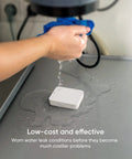 Smart Water Leak Detector 4 Pack With Zigbee Hub Kits Leak Alarm Works With Alexa And Google Home Ultra Sensitive Water Drip Alerts shown detecting water under sink on a surface with hand pouring water.