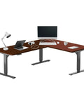 Hella Spacious Electric Height Adjustable L Shaped Corner Standing Desk Featuring A Smooth Glide Motor And Rock Solid Black Frame Ideal For Dual Monitor Setups with wood laminate top and dual screens.