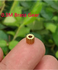 Close-up of a 0.3M brass gear on a fingertip, part of the 10pcs Brass Gears 15T Modulus 0.3M 1.98mm Bore gear set for models.