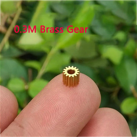 Close-up of a 0.3M brass gear on a fingertip, part of the 10pcs Brass Gears 15T Modulus 0.3M 1.98mm Bore gear set for models.
