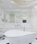 Luxurious marble bathroom with modern fixtures and white freestanding bathtub under a crystal chandelier