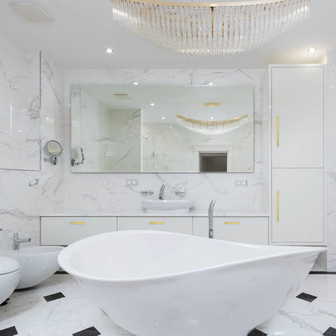 Luxurious marble bathroom with modern fixtures and white freestanding bathtub under a crystal chandelier