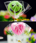 Clear Cake Pop Bags 3x5 Inches, 300 Pcs With Twist Ties, 1.4 Mil OPP Plastic Treat Bags wrapped around smiley and heart-shaped pops
