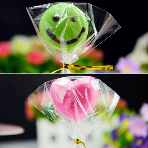 Clear Cake Pop Bags 3x5 Inches, 300 Pcs With Twist Ties, 1.4 Mil OPP Plastic Treat Bags wrapped around smiley and heart-shaped pops