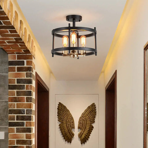 Farmhouse 3 Light Semi Flush Mount Ceiling Light Fixture in Matte Black and Gold Finish with Openwork Circle Frame for Living Room Entryway Kitchen Totally Chic Rustic Modern Style installed in hallway with brick accent wall and golden wings decor.