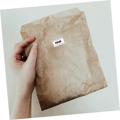 Brown paper bag with Self Adhesive Price Tag Labels For Price Tag Machine, 10 Rolls, 6000 Pieces, Bulk Retail Pricing Tags attached.