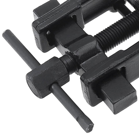 Close-up of a black carbon-steel two-jaw gear puller with a threaded screw