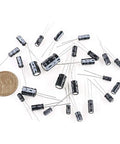 545Pcs Electrolytic Capacitors Assorted Kit With 10V 16V 25V 50V Range Labeled 0.1uF To 1000uF with coin for size reference