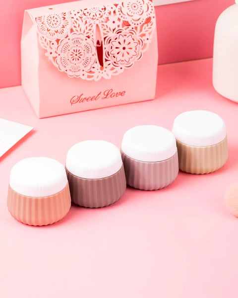TSA Approved Travel Containers Four Pack With Leak Proof Silicone Jars and Rose Gold Cosmetic Bag on a pink background