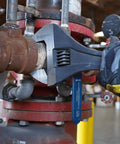24 Inch Adjustable Wrench With Raised Head And Wide Grip For A Broad Range Of Fasteners, used on a pipe in an industrial setting.