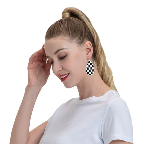 Model wearing Black And White Checkerboard Teardrop Leather Earrings For Women, faux PVC with silver hooks, in profile view.
