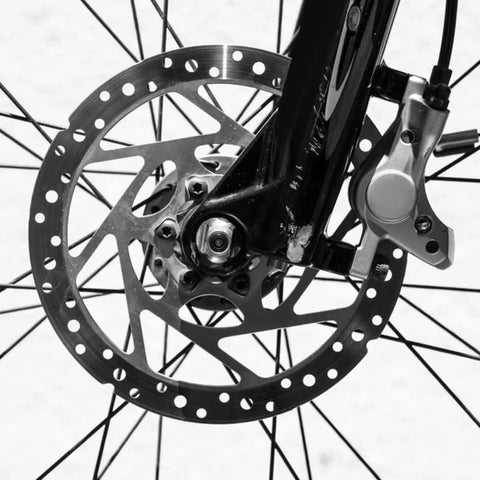 Close-up of a mountain bike disc brake caliper with hardened aluminum, showcasing smooth rotor design and cable assembly.