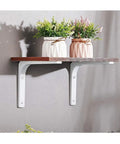 Rock Solid White Heavy Duty L Brackets For Wall Shelves 8 By 6 Inch thick steel shelf support holding a wooden shelf with potted plants.